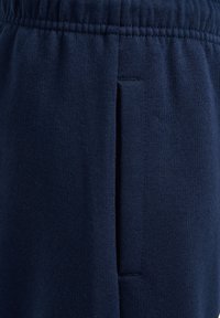 Dunkelblaue Strickhose mit elastischem Bund und vertikalem Seitentaschendetail.