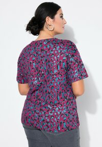 Top de manga corta en púrpura con estampado de leopardo en teal y negro, con un corte holgado y un escote redondeado. Tejido suave y texturizado.