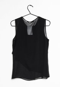 Blouse noire sans manches sur un cintre, faite d'un tissu léger et transparent. Dotée d'un décolleté en forme de trou de serrure et d'une coupe ample et fluide.