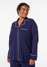 Set di pigiama blu navy con rifiniture bianche, camicia con bottoni dotata di taschino sul petto e maniche lunghe. Tessuto morbido con una vestibilità rilassata.