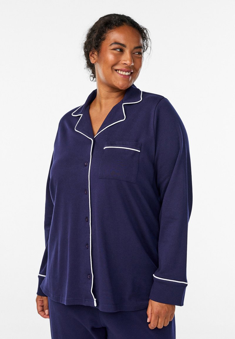 Set di pigiama blu navy con rifiniture bianche, camicia con bottoni dotata di taschino sul petto e maniche lunghe. Tessuto morbido con una vestibilità rilassata.
