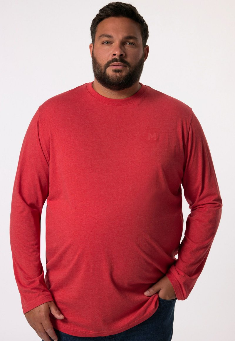Rotes langärmliges T-Shirt aus weichem Stoff, mit Rundhalsausschnitt und minimalem Branding auf der Brust, kombiniert mit blauen Jeans.