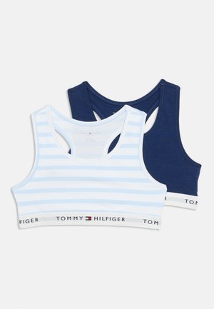 Deux soutiens-gorge de sport pour filles Tommy Hilfiger, l'un bleu clair avec des rayures blanches, l'autre bleu marine uni, tous deux avec des bandes élastiques brandées.