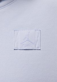 Jasnoniebieska bluzka z dresówki z naszywką z logo Jumpman i napisem "FLIGHT" w dopasowanej nitce.