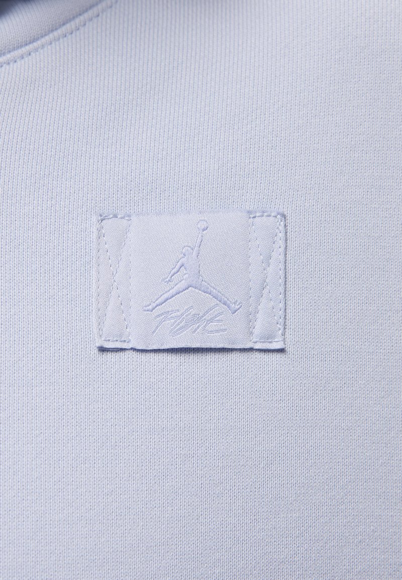 Jasnoniebieska bluzka z dresówki z naszywką z logo Jumpman i napisem "FLIGHT" w dopasowanej nitce.