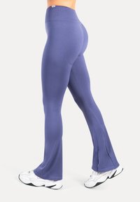 Leggings viola a zampa con una vita alta e un tessuto liscio ed elastico. Presentano una leggera lucentezza e uno spacco sull'orlo.