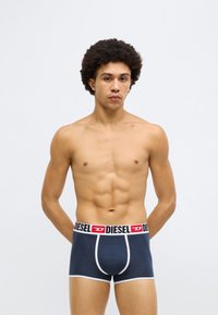 Boxeri bleumarin cu accente albe, având o talie cu logo contrastant. Confecționați dintr-un material elastic, cu un design ajustat și buzunar conturat.