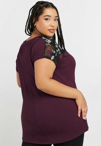 Burgundy toppi suurusele pluss, lühikeste varrukatega, kus on mustast võrgust ja lilleline tikand õlgadel; sile materjal ja kumer alläär.