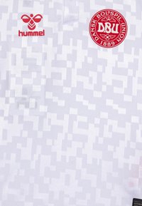 Vit fotbollströja med ett pixelerat mönster, röd Hummel-logga och en cirkulär DBU-patch med text. Tillverkad av andningsbart material.
