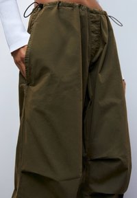 Olijfgroene, losse broek gemaakt van lichtgewicht, gestructureerde stof met een elastische tailleband en zijzakken.