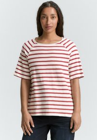 Cremefarvet t-shirt med røde vandrette striber, med en bred halsudskæring og korte ærmer. Casual, afslappet pasform med blød tekstur.