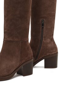 Bruine suède kniehoge laarzen met een gestapelde hak, voorzien van een zijrits en een zachte textuur, ontworpen voor comfort en gebruiksgemak.