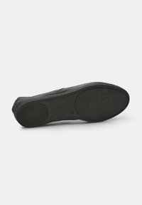 Fekete sneaker talp texturált gumival a tapadás érdekében, lapos kialakítással és lekerekített sarokkal. Különlegessége egy sima, matt felület.