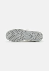 Suela de zapato en caucho blanco con patrones grises texturizados. Presenta un borde redondeado y una superficie lisa, diseñada para proporcionar tracción y estabilidad.