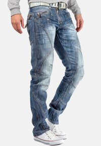 Jeans en denim de lavage bleu clair avec une texture déchirée, des coutures contrastantes, plusieurs poches zippées et un design slim-fit.