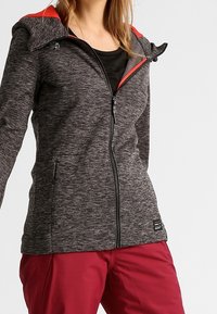 Czarna szara kurtka z zamkiem błyskawicznym i czerwonymi akcentami na kapturze, z fakturowanym wykończeniem i dwiema bocznymi kieszeniami.