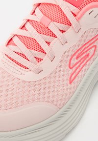 Scarpa sportiva rosa con tomaia in mesh e dettagli sintetici. Caratterizzata da lacci tono su tono e suola testurizzata. Logo del marchio di rilievo in rosa a contrasto.