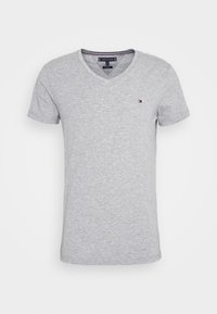 Graues kurzärmliges V-Neck T-Shirt aus weicher Baumwolle, mit einem kleinen farbigen Logo auf der linken Brust und einer schlichten, glatten Textur.