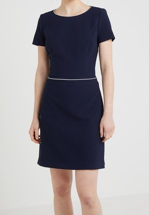 Abito blu navy a maniche corte con tessuto testurizzato, busto aderente e una bordatura bianca a contrasto in vita. Taglio fino al ginocchio.