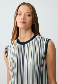 Ärmellose Bluse mit runder marinefarbener Ausschnitt, die vertikale Streifen in Blau, Creme und Marine zeigt. Weicher Stoff, leichtes Material.