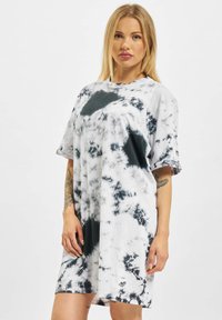 Oversized kortärmad klänning i grå och svart tie-dye-mönster, tillverkad av mjuk bomullsblandning, med rund halsringning och broderad logotypdetalj.
