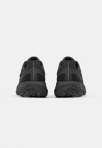 Black athletic shoes with a textured upper, rounded heel, and thick outsole. Features a streamlined shape and minimalistic design.