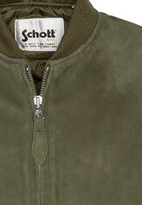 Olijfgroen suède bomberjack met een zilveren rits, geribbelde kraag en Schott NYC-label op de binnenkant van de hals.