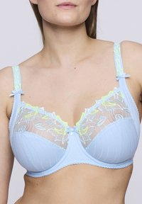 Ljusblå bh med genomskinliga, broderade spetskupor, med blommönster i gult och ljusblått. Justerbara band med rosetter.