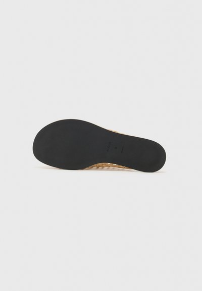 Sandale avec une semelle en caoutchouc noir texturé et un dessus tissé en or. Présente un design ouvert pour la respirabilité et la flexibilité.