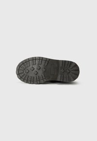 Semelle de chaussure en caoutchouc noir avec un motif de semelle rugueux, présentant des sections rectangulaires et en forme de losange pour une meilleure traction et stabilité.