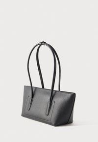 Borsa in pelle nera con trama, con due manici lunghi e arrotondati e un corpo rettangolare leggermente trapezoidale su uno sfondo neutro.