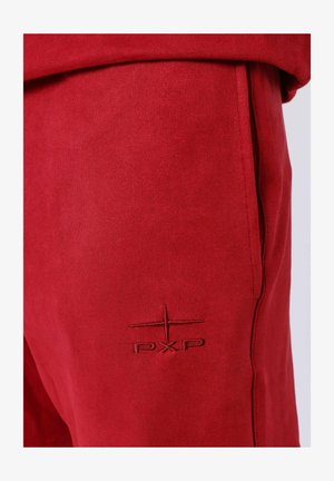 Joggers de ante rojo con bolsillos laterales, presentan un logo PXP bordado en tonos. Textura suave con un ajuste entallado y costuras cuidadas.