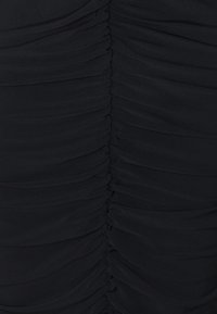 Musta mekko, jossa on kerätty kangas luomassa ryppyistä pintaa etuosaan. Sileä, joustava materiaali korostaa muotoilua.