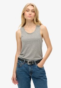 Szary top na ramiączkach wykonany z miękkiego materiału, z zaokrąglonym dekoltem i bezrękawowym fasonem. Połączony z denimowymi spodniami o wysokim stanie i czarnym paskiem.