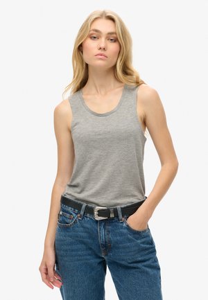 Canotta grigia realizzata in tessuto morbido, con scollatura rotonda e design senza maniche. Abbinata a jeans in denim a vita alta e una cintura nera.