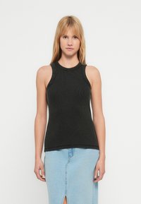 Black ribbed sleeveless top with a round neckline. The fabric is textured and fitted, complemented by a slightly fitted silhouette.