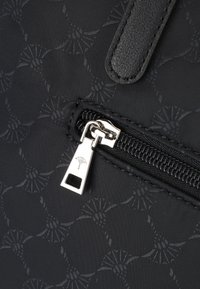 Svart nylonväska med ett mönstrat tyg, med en silverblixtlås och dragflik som framhäver designen. Släta läderdetaljer ingår.