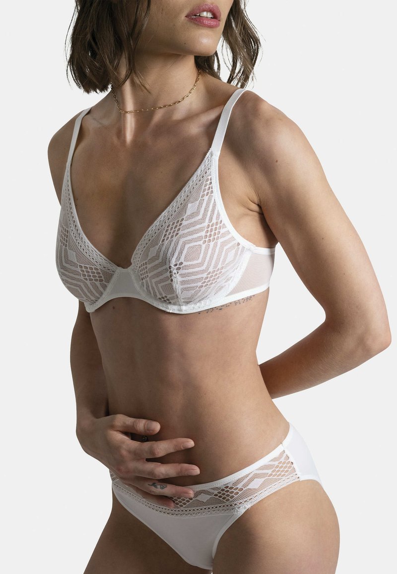 Ensemble de lingerie en dentelle blanche avec des motifs géométriques, matériau doux et détails en maille contrastés. Bralette avec des bonnets triangulaires et culottes assorties.
