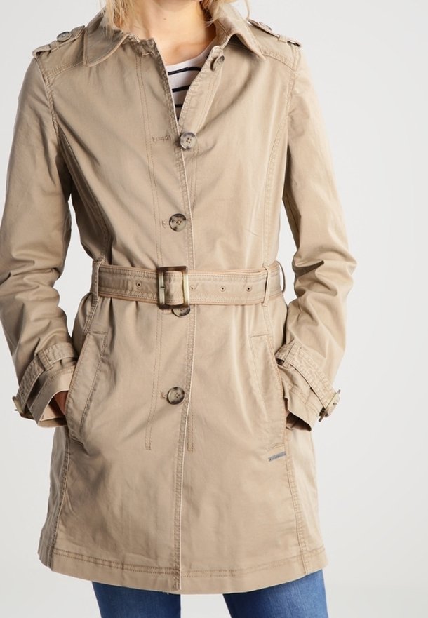 Beige trenchcoat met een riem in de taille, schouderepauletten en knoopsluiting. Twee zijzakken en een gladde, gestructureerde stof.