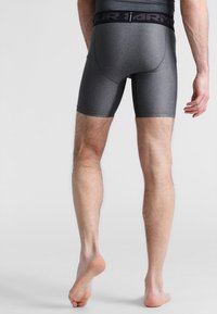 Boxer shorts atletici grigi con un tessuto liscio e testurizzato e una vita elasticizzata nera che presenta il nome del marchio in evidenza.