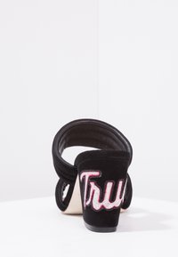 Černé semišové sandály na podpatku s otevřenou zadní částí. Disponují širokými popruhy a na podpatku je vyšitý nápis "True" v růžové barvě. Texturovaný povrch.