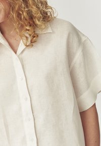 Lichtgekleurde linnen shirt met een relaxte pasvorm, korte mouwen en een knoopsluiting aan de voorkant. Het materiaal heeft een gestructureerde afwerking.