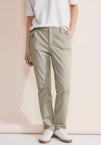 Beige, recht gesneden broek met knoopsluiting en zijzakken; gemaakt van gladde stof, met een subtiele glans en decoratieve ringdetails.