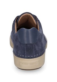 Chaussure en suède bleu marine avec un dos arrondi, semelle en caoutchouc beige et accents en cuir près du talon, présentant des détails de couture visibles.