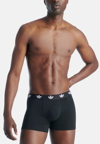 Svarta boxerkalsonger med en åtsittande design och en kontrasterande elastisk midja med vita logotypdetaljer. Slät tyg med en lätt lyster.