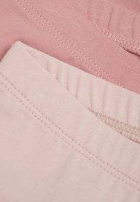 Två lager av tyg i nyanser av rosa, med slät textur och fint sömnadsdetaljer vid midjebanden.