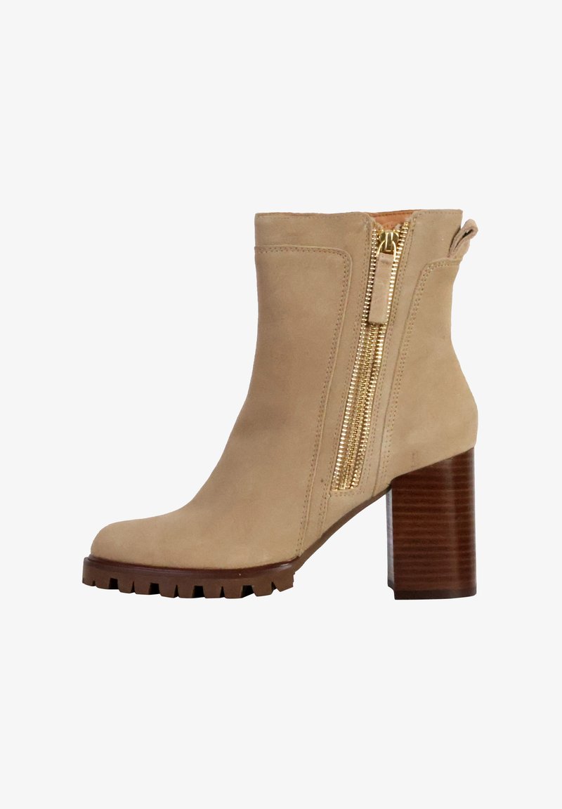 Bottine en suède beige avec un talon en bois brun épais et une fermeture éclair dorée sur le côté. Présente un bout arrondi et une semelle texturée.