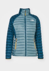 Doudoune bleu et bleu clair avec zip intégral, tirettes orange et logo The North Face sur la poitrine, affichée sur fond blanc.