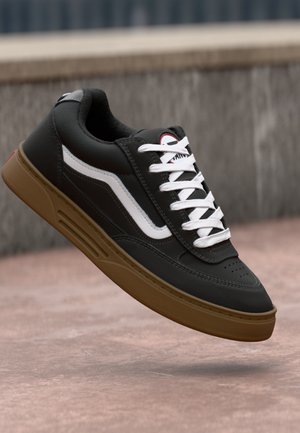 Black leather sneaker with white laces and side accents. Features a perforated toe and a brown rubber sole with textured detailing.