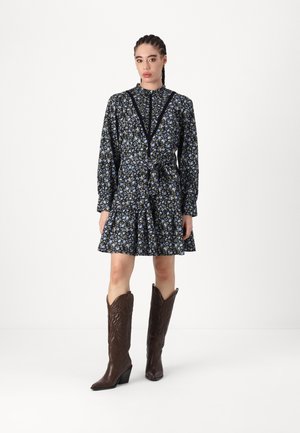Floral dress with long sleeves, blue and green flowers on a dark background, cinched waist, and flared skirt. Paired with brown cowboy boots.